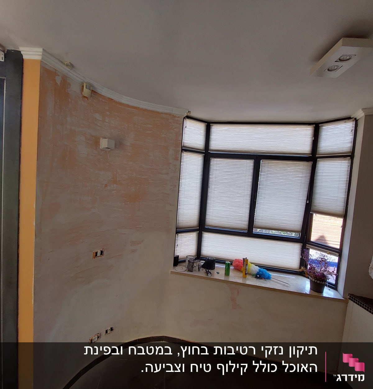 קיר צבוע חלקית עם חלון גדול וכלי עבודה על אדן החלון